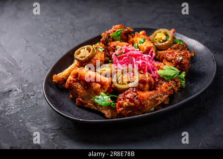 Gegrillte Zitronen- und Knoblauch-Hähnchenflügel mit eingelegtem Wurzelgemüse und Jalapenos. Asiatische Küche. Stockfoto
