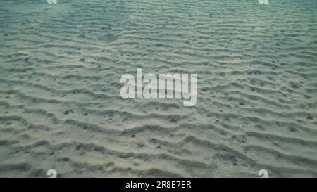 Sandiger, weißer Boden mit Sonnenschein am Morgen. Natürlicher Hintergrund aus der Unterwassertiefe, Rotes Meer, Ägypten Stockfoto