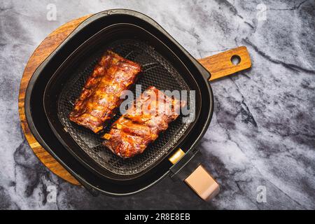 Moderne Küche – Zubereitung saftiger Spareribs mit Honigsauce im Airfryer, Grillfleisch Stockfoto