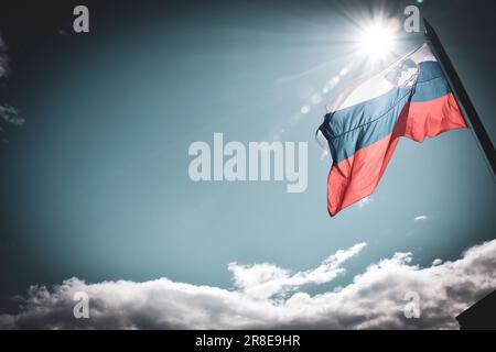 Flatternde slowenische Flagge gegen die Sonne - Bled, Slowenien Stockfoto