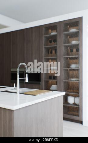 Minimalismus in der Küche. Holzküche mit großer langer Insel und Barhockern. Stockfoto