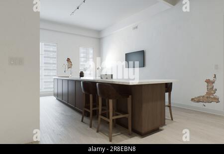 Minimalismus in der Küche. Holzküche mit großer langer Insel und Barhockern. Stockfoto
