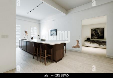 Minimalismus in der Küche. Holzküche mit großer langer Insel und Barhockern. Stockfoto