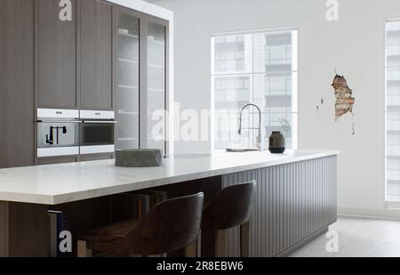 Minimalismus in der Küche. Holzküche mit großer langer Insel und Barhockern. Stockfoto