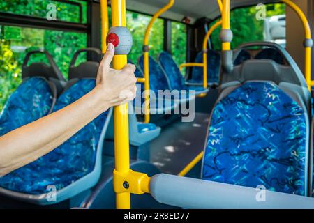 In einem Stadtbus. Leere Bushaltestelle. Bus mit blauen Sitzen und gelben Handläufen. Öffentlicher Nahverkehr. Stockfoto