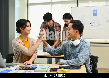 Foto von zwei glücklichen Webdesignern, die sich gegenseitig High Five geben, eine Feier für Teamwork Stockfoto