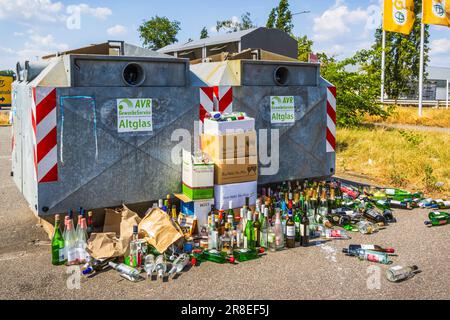 Hockenheim, Deutschland - 18. Juni 2023: Überfüllte Glasbehälter auf einer Straße. Recycling-Konzept und Müllentsorgung. Übersetzung: Kommerzieller Dienst, Stockfoto