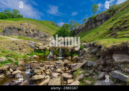 Blick nach Swinnergill und die hölzerne Brücke, die den Fluss von Swaledale im Yorkshire Dales National Park überquert. Stockfoto