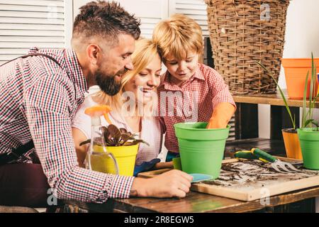 Glückliche Familie, die Sprossen in einen Pflanzentopf pflanzt. Der kleine süße Junge hilft seinen Eltern. Teamwork und Familienverein-Konzept. Umweltschutz und Stockfoto