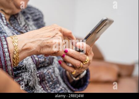 Ältere Frau mit Smartphone, Mobiltelefon in zerknitterten weiblichen Händen, Nahaufnahme. Konzept der Online-Kommunikation im Ruhestand. Hochwertiges Foto Stockfoto