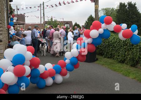 Queen Elizabeth II. Platinum Jubilee Street Party-Feiern in Robbs Lane, Lowick. Die Straße war mit einer Reihe roter, weißer und blauer Ballons abgesperrt. Die Dorfbewohner wurden gebeten, ihr eigenes Essen mitzubringen und einige zu teilen. Etwa 50 Personen waren anwesend. Lowick, Northamptonshire, England, 3. Juni 2022. HOMER SYKES Stockfoto