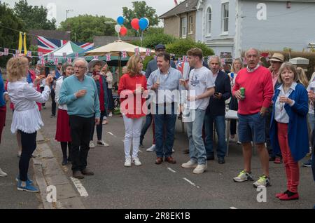 Singen Sie die Nationalhymne, Gott rette die Königin. Winchester, Hampshire, England, 5. Juni 2022. Queen Elizabeth II. Platinum Jubilee Straßenfest in der Grafton Road. Die Straße war geschlossen, mit Fähnchen dekoriert. Die Anwohner wurden ermutigt, rot, weiß und blau zu tragen. Um 12 Uhr gab es einen lokalen Toast und drei Anfeuerungen für die Königin und dann das Singen der Nationalhymne. HOMER SYKES AUS DEN 2020ER JAHREN Stockfoto