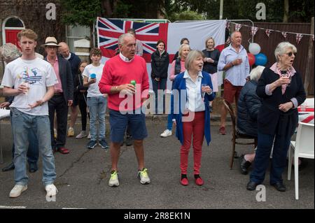 Trägt rot-weiß-blau. Nachbarn singen die Nationalhymne, Gott rette die Königin. Winchester, Hampshire, England, 5. Juni 2022. Queen Elizabeth II. Platinum Jubilee Straßenfest in der Grafton Road. Die Straße war geschlossen, mit Fähnchen dekoriert. Die Bewohner der Nachbarschaft wurden dazu ermutigt, rot, weiß und blau zu tragen. Um 12 Uhr gab es einen lokalen Toast und drei Anfeuerungen für die Königin und dann das Singen der Nationalhymne. HOMER SYKES AUS DEN 2020ER JAHREN Stockfoto