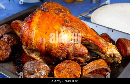 Im Ofen gebackenes Schweinekeule mit Beilage aus Kartoffeln in Backblech Stockfoto