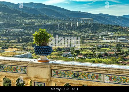 Geschnitzter Handlauf mit Keramikmuster und mit blauem Becken mit Kaktus in der Stadt Santo Stefano di Camastra Stockfoto