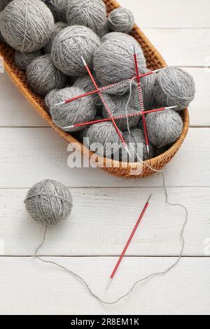 Das Stricken im Kreis auf doppelseitigen Stricknadeln, Garnknäuel im Korb. Stockfoto