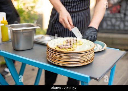 Der Koch bereitet im Restaurant im Freien Kuchen mit Fleisch zu. Catering außerhalb der Anlage Stockfoto