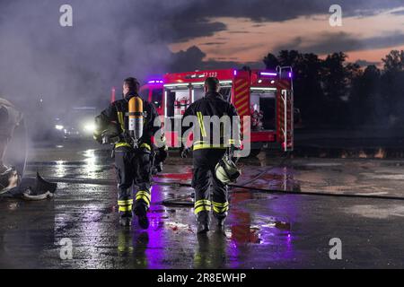 Das Team der tapferen Feuerwehrleute geht zur Kamera. Im Hintergrund Sanitäter und Feuerwehr Rettungsteam bekämpfen Feuer in Autounfall, Versicherung und Rettung von Menschen Stockfoto