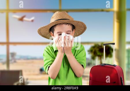 Kind in Hut bläst in Wischtuch leidet an Grippesymptomen am Flughafen. Stockfoto