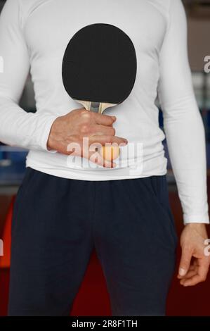 Gekürzter Tischtennisschläger und Ball in der männlichen Hand Stockfoto