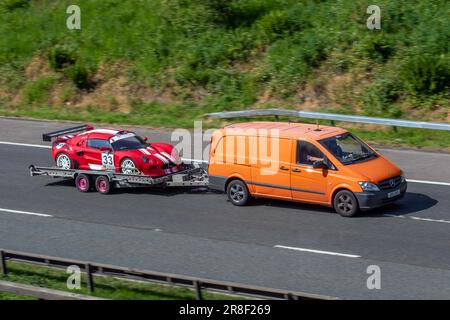 Lotus Motorsport Elise – Honda Supercharged Racing, Rotweißer Rennwagen Lotus Elise Nr. 33 auf einem Anhänger, der von einem orangefarbenen Mercedes Benz Sprinter-Minibus auf der Autobahn M6, Großbritannien, gezogen wird Stockfoto