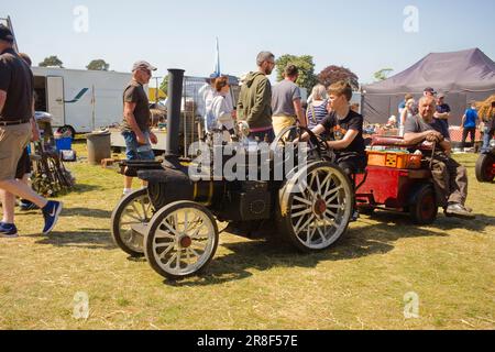 Eine jüngere Person, die auf der Scampton Show in Yorkshire eine Miniatur-Zugmaschine fährt Stockfoto