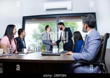 Eine Gruppe indischer Geschäftsleute, die sich nach einem Meeting im Sitzungssaal die Hand schütteln. Stockfoto