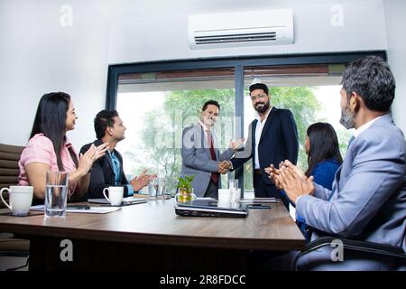 Eine Gruppe indischer Geschäftsleute, die sich nach einem Meeting im Sitzungssaal die Hand schütteln. Team applaudiert Mitarbeiter für gute Arbeit im Unternehmen Stockfoto