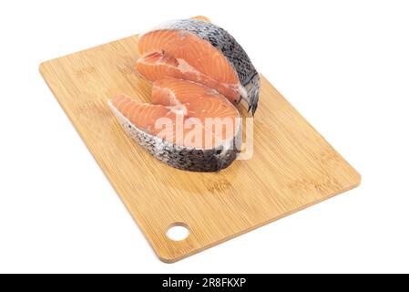 Frisch portionierte Lachssteaks auf einem Schneidebrett auf weißem Hintergrund. Speicherplatz kopieren. Stockfoto