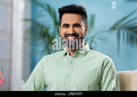 Glücklicher lächelnder indianer, der zu Hause auf dem Sofa in die Kamera schaut - Konzept von selbstbewusstem, fröhlichem Ausdruck und positiven Emotionen. Stockfoto