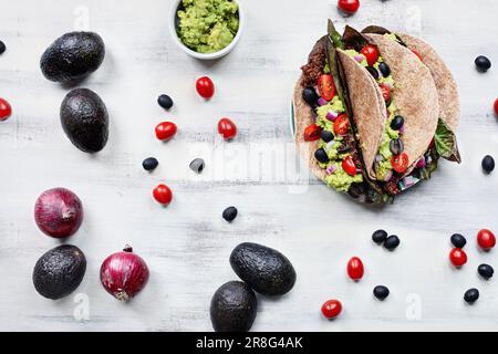 Ein gesundes Mittag- oder Abendessen mit veganischem/vegetarischem Taco-Wrap aus roter Quinoa mit Taco-Saison, Römersalat, Tomaten, Guacamole. Stockfoto