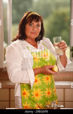 Frau mit einem Glas Wasser mit Zitronensaft, Zitrussaft, Haarband, frisch gepresst Stockfoto