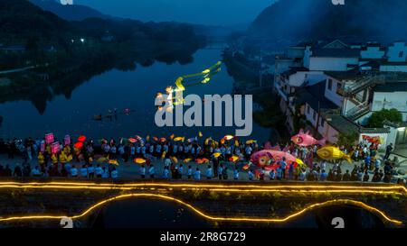 (230621) -- NINGGUO, 21. Juni 2023 (Xinhua) -- Dieses Luftfoto wurde am 16. Juni 2023 aufgenommen und zeigt eine Laterne in Hule Town in Ningguo, Ostchina Provinz Anhui. Hule Town, eine antike Stadt in der Provinz Anhui im Osten Chinas, hat eine Tradition der Laternen-Aufführung, um Festivals zu feiern. Kurz vor dem Dragon Boat Festival führen die Dorfbewohner Laternen mit Laternen in Form von Fischen und Drachen auf und platzieren Lotuslaternen im Fluss. Eine Reihe von Aktivitäten wie das Bankett mit langen Tischen und die Laternen-Messe wurden durchgeführt, um Touristen von zu Hause und A anzuziehen Stockfoto