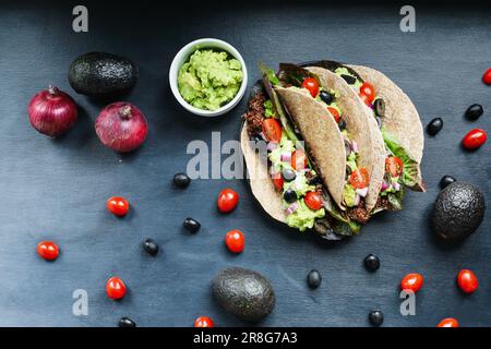 Ein gesundes Mittag- oder Abendessen mit veganischem/vegetarischem Taco-Wrap aus roter Quinoa mit Taco-Saison, Römersalat, Tomaten, Guacamole. Stockfoto