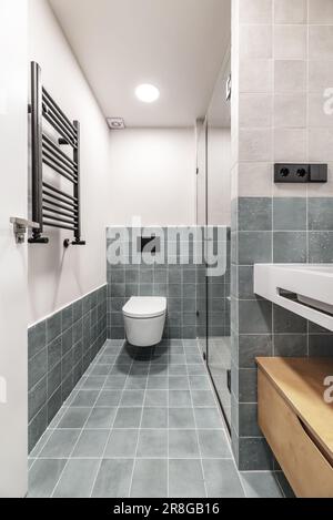 Badezimmer mit Toiletten und Wandeinheiten mit kleinen quadratischen grünen Fliesen und schwarzen Details Stockfoto