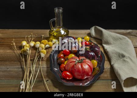 Stillleben mit Tomaten verschiedener Sorten mit etwas Olivenöl auf einer Edelstahlschale Stockfoto