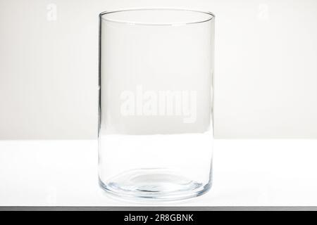 Ein großer, leerer Glasbehälter ohne Deckel auf einem weißen Holztisch Stockfoto