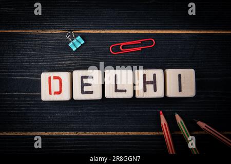 DELHI. Name der Stadt aus Buchstaben auf holzstrukturiertem Hintergrund. Stockfoto