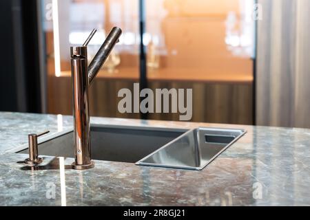 Ein moderner Wasserhahn und ein Waschbecken in einer trendigen Küche. Mitten im Bild Stockfoto