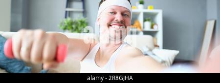 Ein emotional glücklicher, aufgeregter junger Mann, der mit Kurzhanteln posiert und Selfie macht Stockfoto