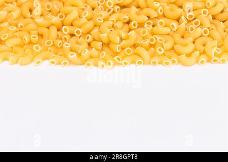 Ungekochte Chifferi Rigati Pasta auf dem weißen Tisch. Fett und ungesunde Lebensmittel. Klassische Trockene Makkaroni. Italienische Kultur und Küche. Rohe Pasta Stockfoto