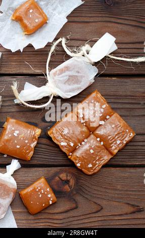 Gesalzene Karamell-Toffee-Süßigkeiten mit Salzflocken auf rustikalem Holzhintergrund Stockfoto