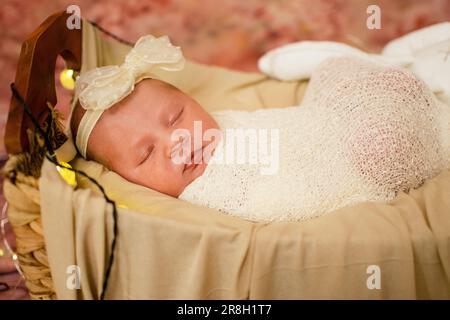 Süßes, gesundes, kaukasisches, neugeborenes Baby Mädchen, das schläft, eingewickelt in eine Windel und Bogen. Stockfoto