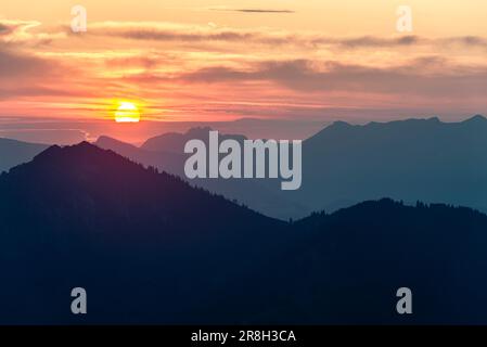 Farbenfroher Sonnenaufgang hinter dem Kampenwand im Chiemsee in den Bayerischen Alpen, Tirol, Österreich Stockfoto