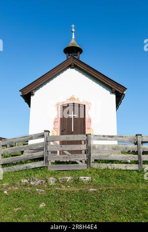 Kapelle mit weißer Fassade auf Alpen im Tiroler Gebirge im Sonnenlicht vor blauem Himmel, Grabenbergalm, Tirol, Österreich Stockfoto