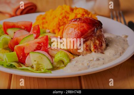 Gefüllte Hühnerschenkel, in Speck mit Süßkartoffeln und Salat eingewickelt. Stockfoto