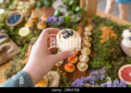 Weiblicher Gast auf einer rustikalen Party im Freien mit Mini-Pavlova-Dessert mit frischen Blaubeeren Stockfoto