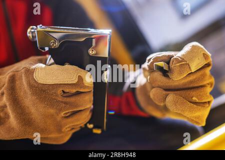 Nahaufnahme von Heftpistole und Heavy Duty Staples in den Händen von professionellem Holzarbeiter. Holzbearbeitungswerkzeuge und -Ausrüstung. Stockfoto