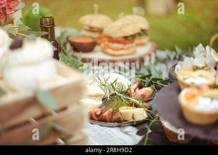 Rustikaler Außenempfang in elegantem Garten mit lokalen Gourmetspeisen. Weibliche Hand gießt natives Olivenöl Ofen Antipasti. Italienische Hochzeit Stockfoto