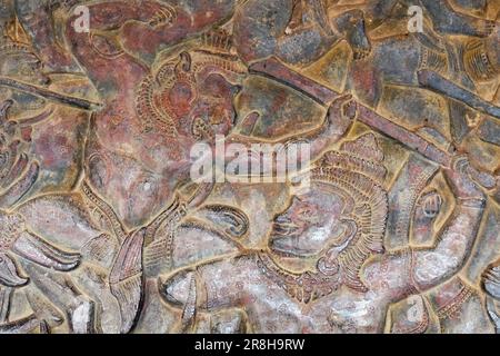 Antike Kunst auf Stein eingefangen: Kampfszenen aus der hinduistischen Mythologie, die auf die Wände eines alten Khmer-Tempels geätzt wurden und als Zeugnis der Zeit stehen. Stockfoto